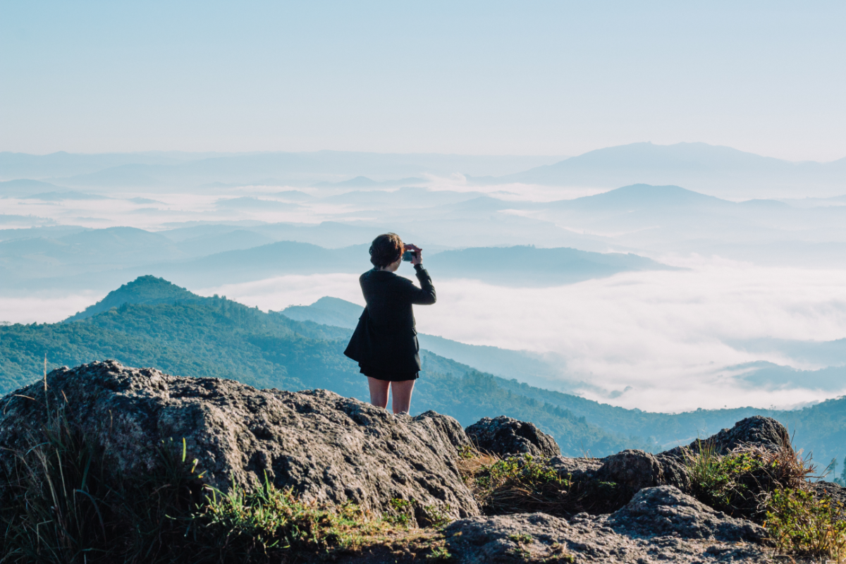 Una mujer mira las vistas en la cima de un monte con su ropa Salomon. (Fuente: Canva) ella-hoy.es